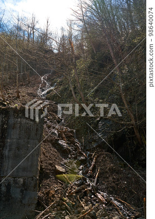 A huge rock fell from the mountains onto the road, destroying the asphalt and blocking half of the roadway A huge rock fell from the mountains onto the road, destroying the asphalt and blocking half of the roadway 98640074