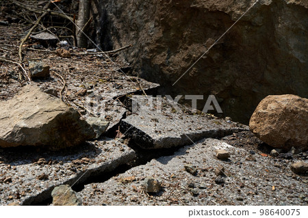 A huge rock fell from the mountains onto the road, destroying the asphalt and blocking half of the roadway A huge rock fell from the mountains onto the road, destroying the asphalt and blocking half of the roadway 98640075