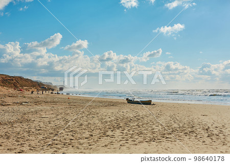Wooden boat abandoned on the seashore a 98640178