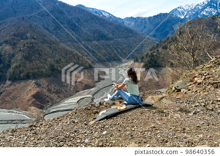 A girl on a picnic with an incredible natural view of the mountains and a dehydrated mountain river. Gorgeous scenery 98640356