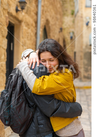 A young girl hugs a guy standing on the street 98640361