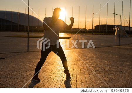 A man trains boxing at sunset outdoors. 98640876