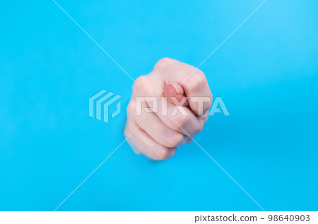 Female hands sticking out through a hole on a blue background.  98640903