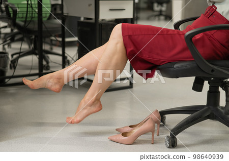 Caucasian woman took off her heels while sitting in the office. Cropped portrait. Caucasian woman took off her heels while sitting in the office. Cropped portrait. 98640939