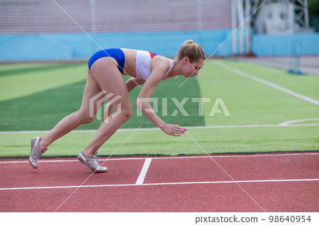 Young caucasian woman is engaged in jogging at the stadium outdoors. Young caucasian woman is engaged in jogging at the stadium outdoors. 98640954