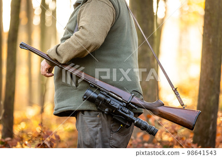 Hunter or ranger with a professional, nightvision hunting gun and hunting form to hunt in an autumn forest, hunting concept Hunter or ranger with a professional, nightvision hunting gun and hunting form to hunt in an autumn forest, hunting concept 98641543