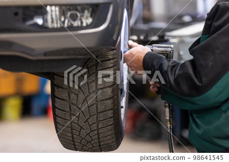 Car, auto mechanic changing tires, wheels on the car by pneumatic wrench, service center Car, auto mechanic changing tires, wheels on the car by pneumatic wrench, service center 98641545