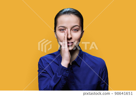 Young teenage woman whispering secret, over yellow background 98641651