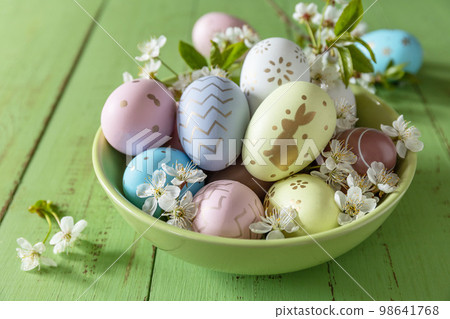 Easter composition. Branches of a blooming apple tree, handmade Easter colorful eggs on a pastel rustic wooden table. Happy Easter Holidays. 98641768
