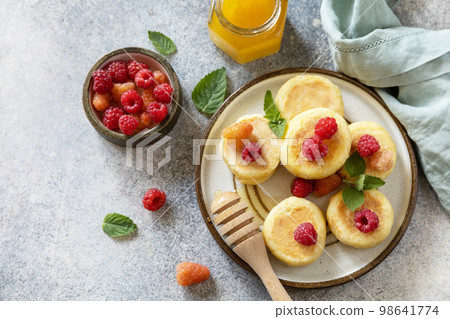 Homemade cottage cheese pancakes gluten free (syrniki, curd fritters) with berries on a stone background. Ricotta pancakes, morning breakfast table. Copy space. Homemade cottage cheese pancakes gluten free (syrniki, curd fritters) with berries on a stone background. Ricotta pancakes, morning breakfast table. Copy space. 98641774