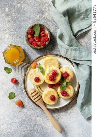Homemade cottage cheese pancakes gluten free (syrniki, curd fritters) with berries on a stone background. Ricotta pancakes, morning breakfast table. View from above. Homemade cottage cheese pancakes gluten free (syrniki, curd fritters) with berries on a stone background. Ricotta pancakes, morning breakfast table. View from above. 98641775