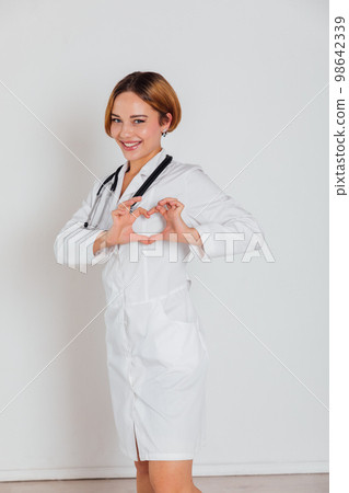 woman doctor in white coat with phonendoscope shows heart 98642339