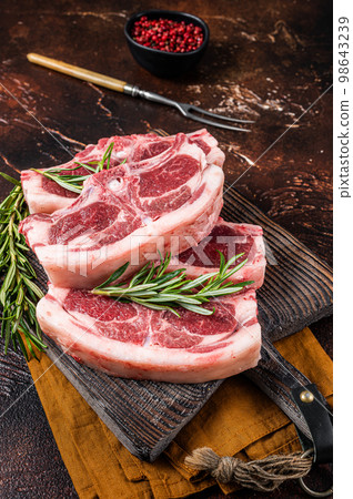 Raw fresh saddle of lamb mutton with herbs and spices on butcher board. Dark background. Top view 98643239