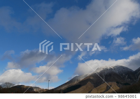 厚厚的雲層和小雪覆蓋的冬日山巒和路燈 98645001