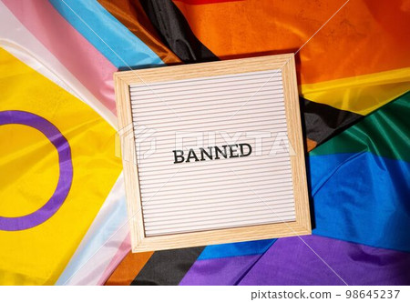 BANNED text frame on Rainbow LGBTQIA flag made from silk material. Symbol of LGBTQ pride month. Equal rights. Peace and freedom. Support LGBTQIA community BANNED text frame on Rainbow LGBTQIA flag made from silk material. Symbol of LGBTQ pride month. Equal rights. Peace and freedom. Support LGBTQIA community 98645237