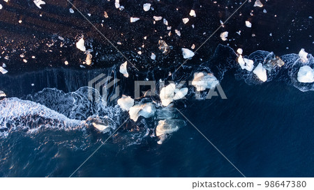 Pure Blue Glacier Ice on Black Sand Beach. Turquoise Sea Water. Icebergs at Diamond Beach in Iceland 98647380