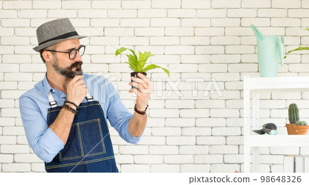 An elderly man handsome with have mustache wearing glasses is happy with tree care. is a hobby of gardening at home, living happily after retirement. Concepts nature and environment An elderly man handsome with have mustache wearing glasses is happy with tree care. is a hobby of gardening at home, living happily after retirement. Concepts nature and environment 98648326