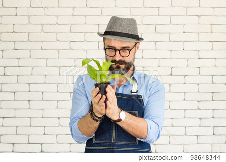 An elderly man handsome with have mustache wearing glasses is happy with tree care. is a hobby of gardening at home, living happily after retirement. Concepts nature and environment 98648344