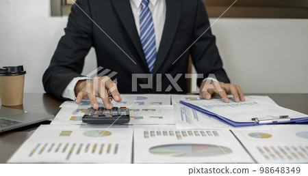 Young Asian businessman financial market analyst sits at their desks and calculate financial graphs showing the results of their investments planning the process of successful business growth 98648349