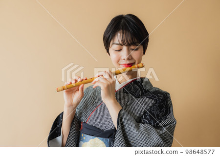 A woman in a kimono holding a Japanese musical instrument Shakuhachi A woman in a kimono holding a Japanese musical instrument Shakuhachi 98648577