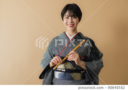A woman in a kimono holding a Japanese musical instrument Shakuhachi 98648582