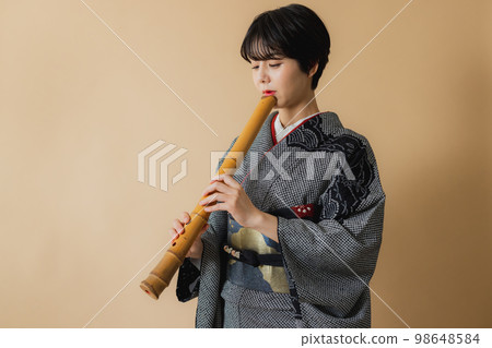A woman in a kimono holding a Japanese musical instrument Shakuhachi A woman in a kimono holding a Japanese musical instrument Shakuhachi 98648584