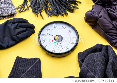 Thermo-hygrometer and winter goods over yellow background Thermo-hygrometer and winter goods over yellow background 98649134
