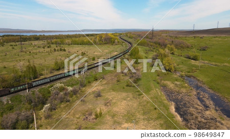 Aerial view of a freight train traveling through the countryside Aerial view of a freight train traveling through the countryside 98649847