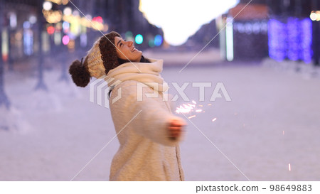 Portrait of young smiling Caucasian woman holding sparklers. Happy cheerful girl outdoors Celebrating New Year holidays vacation. Xmas Christmas winter atmosphere. 3840x2160 Portrait of young smiling Caucasian woman holding sparklers. Happy cheerful girl outdoors Celebrating New Year holidays vacation. Xmas Christmas winter atmosphere. 3840x2160 98649883