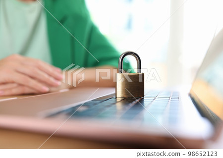 Laptop computer with padlock on office desk and business woman or manager in background. Laptop computer with padlock on office desk and business woman or manager in background. 98652123