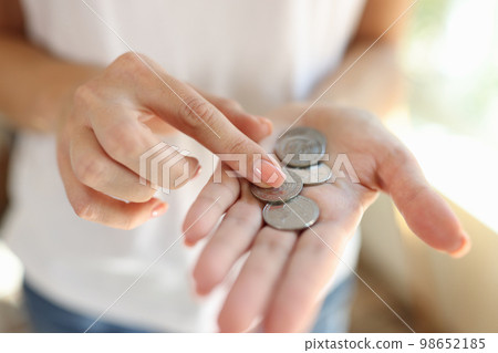 Woman counting small coins in her hands close-up. Woman counting small coins in her hands close-up. 98652185