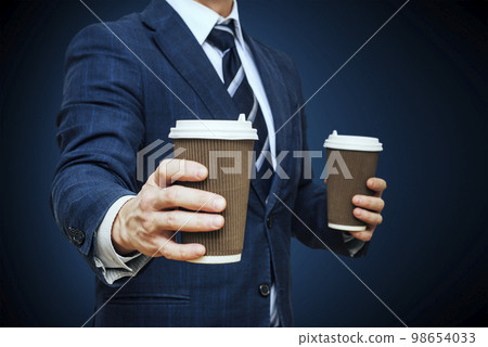Businessman offering coffee in paper cup. Businessman offers a cup of coffee Businessman offering coffee in paper cup. Businessman offers a cup of coffee 98654033