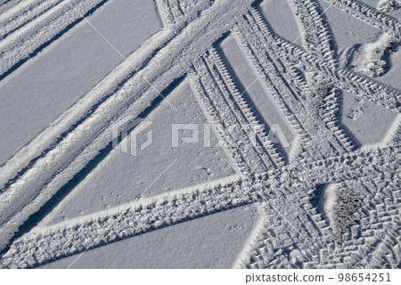 Tire marks on the snow-covered road 98654251