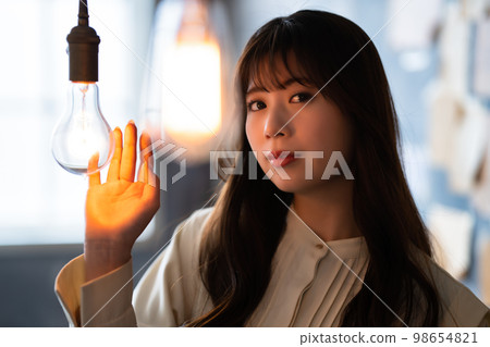 Woman holding her hand over a retro light bulb 98654821