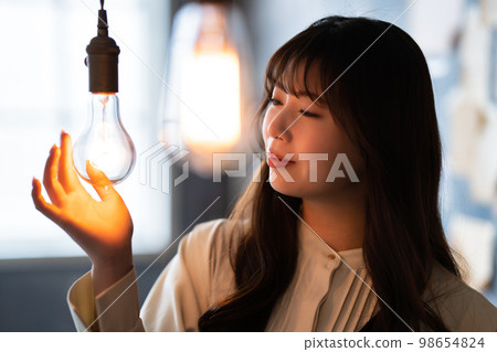 Woman holding her hand over a retro light bulb 98654824