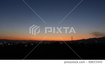 Transmission tower glowing at dusk in the mountains 98655445