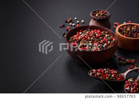 Spice allspice of different colors pink, white, green not ground in a wooden saucer 98657763
