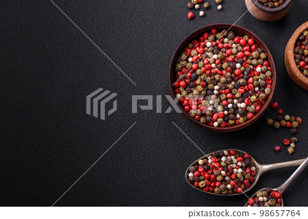 Spice allspice of different colors pink, white, green not ground in a wooden saucer 98657764