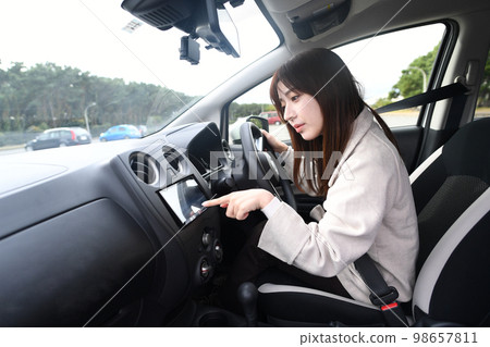 Young woman using car navigation system while driving 98657811