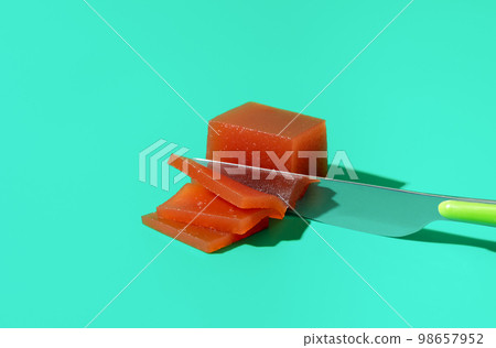 Slicing quince marmalade on a blue background 98657952
