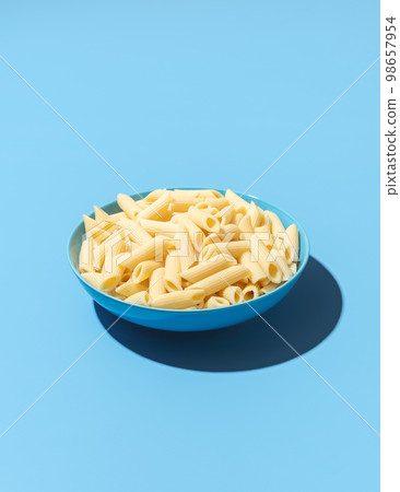 Penne pasta bowl minimalist on a blue background 98657954