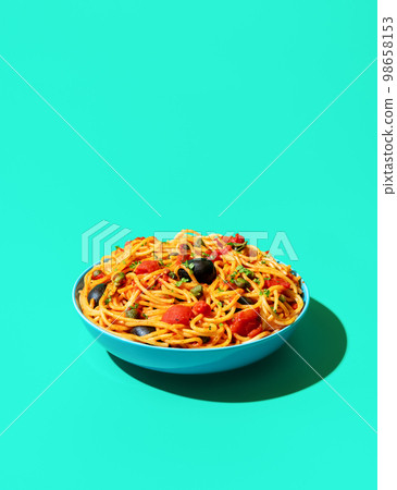 Spaghetti puttanesca bowl minimalist on a green background 98658153
