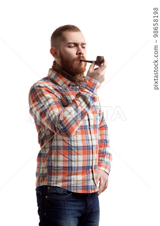 Handsome bearded redhead guy in checked lights up his pipe while isolated on white background  98658198