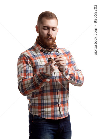 Portrait of handsome bearded redhead man in checked shirt who holds pipe on white background 98658202