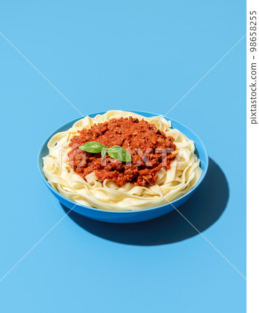 Bolognese pasta dish isolated on a blue background Bolognese pasta dish isolated on a blue background 98658255