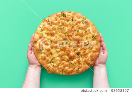 Focaccia with rosemary in woman hands, above view 98658367
