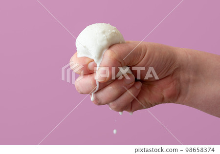 Squeezing mozzarella ball in hand, close up on a purple background Squeezing mozzarella ball in hand, close up on a purple background 98658374