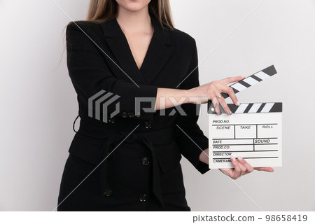 Sensuality beautiful woman with long hair, dressed in black suit in studio, holding clapperboard 98658419
