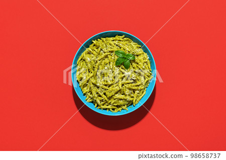 Pasta with pesto sauce, top view on a red background Pasta with pesto sauce, top view on a red background 98658737
