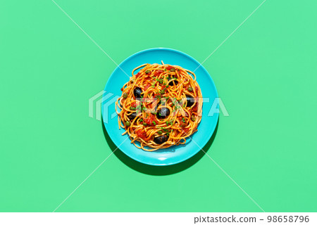 Spaghetti puttanesca plate, above view on a green background 98658796